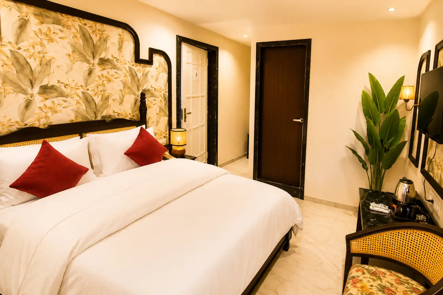 Premium boutique hotel bedroom featuring a king-size bed, white linens, deep red pillows, and custom floral wall paneling at Hotel Casa Brij Boutique Mount Abu.